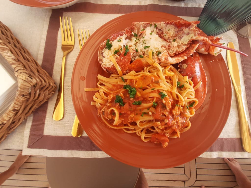 Piatto con aragosta e pasta fresca preparato a bordo.