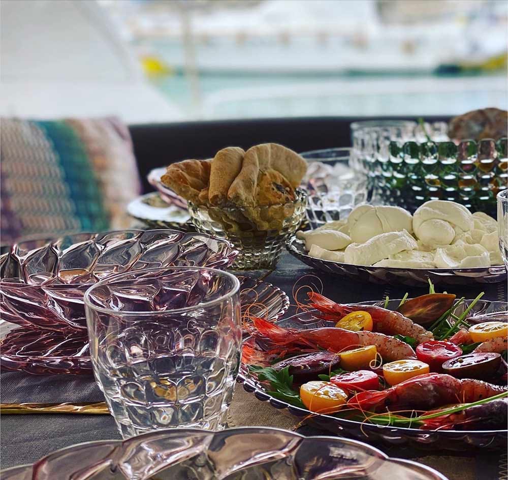 Tavola con antipasti freschi e bicchieri di vetro lavorato.
