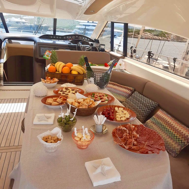 Tavola di accoglienza al timone con frutta, champagne e antipasti.